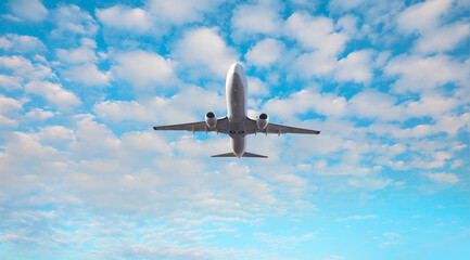 Fototapeta na wymiar White passenger plane soaring towards low clouds - Travel by air transport