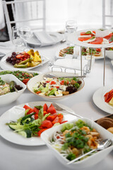 
Beautifully set table in the banquet hall of the restaurant. A table with appetizers for wine, cold dishes and salads. White tablecloths and napkins