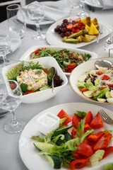 
Beautifully set table in the banquet hall of the restaurant. A table with appetizers for wine, cold dishes and salads. White tablecloths and napkins