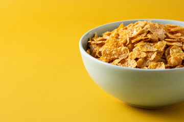 Corn flakes in a blue bowl on yellow background