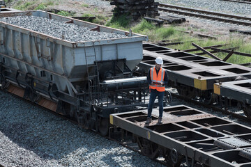 worker railway transportation machinery and equipment. mechanic is standing to check the availability of a rail cargo trey.
