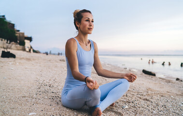 Fototapeta na wymiar Woman in sportswear meditating on beach