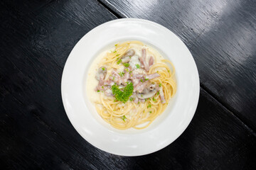 spaghetti on white plate on black wooden background, spaghetti menu concept. Top view.