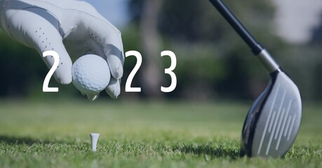 Composition of 2023 number with golf ball placed by golf player on tee on golf course