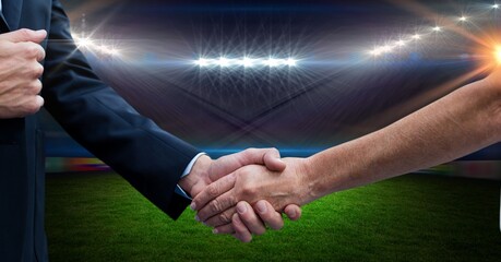 Composition of business people shaking hands over sports stadium