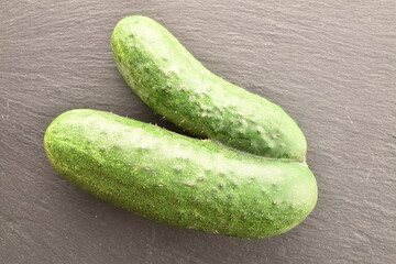 One ripe green custom cucumber on a slate board, close-up, top view.