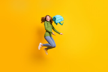 Full length body size photo smiling girl throwing rucksack in air laughing isolated vivid yellow color background