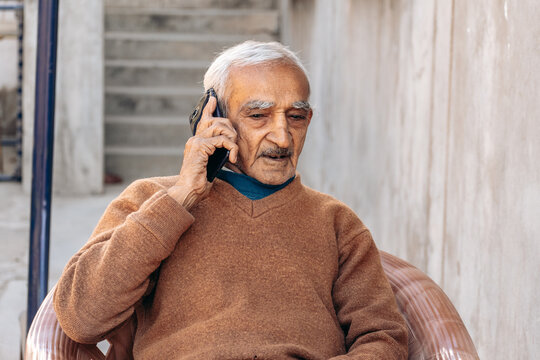 Smiling older man talking on cellphone close up, happy grandfather chatting with relatives or grandchildren, satisfied mature male making phone call, having pleasant conversation
