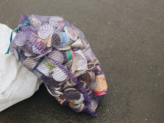 Crushed tin cans in big mesh bag on the pavement ready for recycling. Zero waste. Collection and separating waste