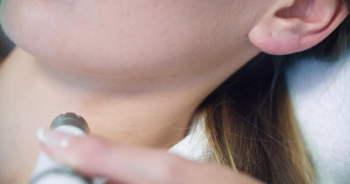 The close-up neck of a female client who is having a non-injection bio-revitalization procedure by using the Dermadrop TDA device.