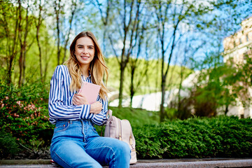 Obraz premium Positive young lady sitting with diary in hands and looking in camera