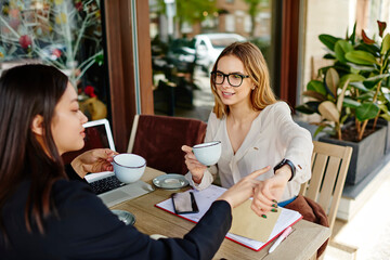 Diverse colleagues drinking cups of beverage during coffee break on terrace