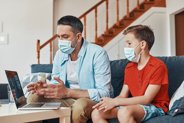 Father and son using laptop to have a video call with doctor while spending time at home