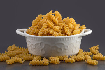 Raw uncooked spiral pasta in bowl. Raw pasta, macaroni, Dry spiral pasta. Delicious pasta or spiral noodles. italian cuisine