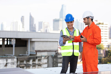 engineers or technicians holding tablet, talking about project with solar panels on the top of the roof