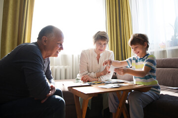 grandparents with grandson  playing  board game together at home. quarantine.  Family having fun playing at home. Family board games. 