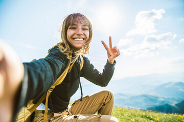 Young woman taking selfie portrait hiking mountains - Happy hiker on the top of the cliff smiling at camera - Travel and hobby concept
