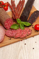 Different types of sausages with tomatoes and herbs on a wooden board. Top view
