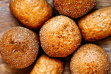 Buns for burgers and sandwiches, sesame bun, buns. Fresh burger bread with sesame seeds on a wooden background. Delicious hamburger buns.