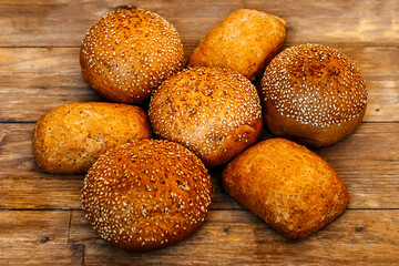 Buns for burgers and sandwiches, sesame bun, buns. Fresh burger bread with sesame seeds on a wooden background. Delicious hamburger buns.