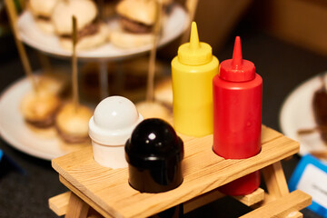 Fototapeta na wymiar Condiments on a mini picnic table in front of mini burgers