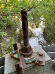 Rusty nut and bolt rod in a park to control water way  of a river and a pond