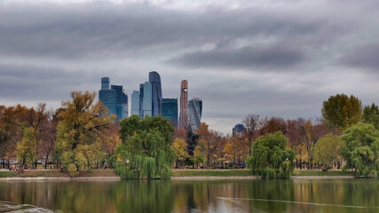 Obraz premium Park Novodevichy Ponds and view of Moscow City. Skyscrapers and cloudy weather. Lake in autumn. Russia. 