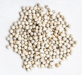 pile of white pepper peppercorns close up on gray