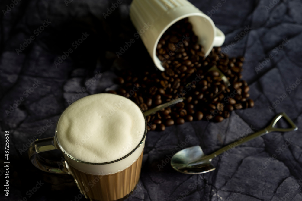 Wall mural hot latte with coffee beans on dark stone background