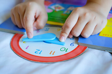 kid play telling time game, young children to learn how to read an analog clock.