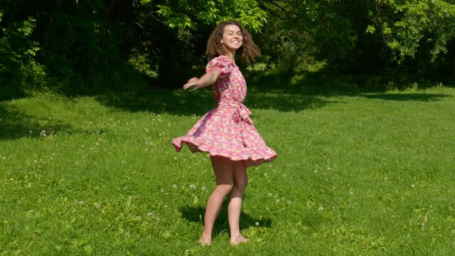 The girl in the dress dances on the lawn