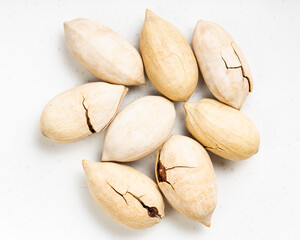 several cracked pecan nuts close up on gray