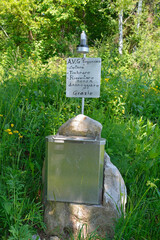 A box containing the summit register on Monte Purgessimo in Udine Province, Friuli-Venezia Giulia, north east Italy. The sign provides usage instructions for the stamp at the top - unscrew, stamp, scr