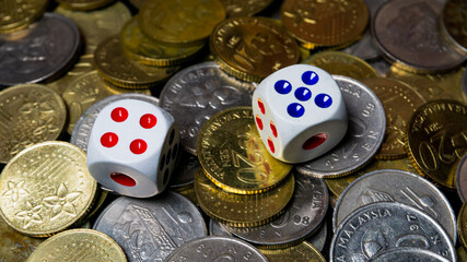 Two dice on a collection of gold and silver Malaysian 20 sen coin. © Aiman Khair