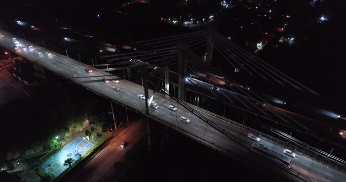 Juan Pablo Duarte and Juan Boch Bridge at night passing over neighborhood, Santo Domingo. Aerial tilt-up ascendent