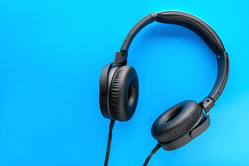 Black wired Headphones on a blue background. Entertainment concept