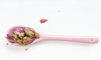 old dried rosebuds in ceramic spoon on plate
