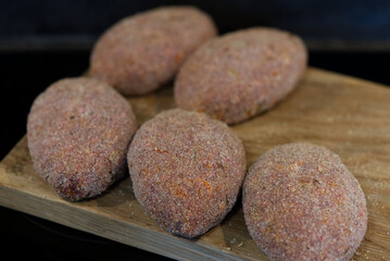 Raw cutlets made of ground beef meat on a rustic chopping board. homemade cutlets