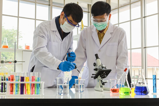 Professional senior doctor scientist teach and guide young scientist droplet liquid solution substance to test chimical with sciene glassware in working laboratory.