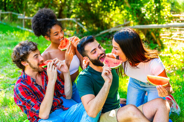 Young people eat watermelon in the park on sunny day