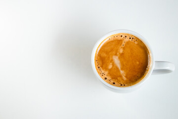 A close up of a white coffee cup with coffee on a white background.