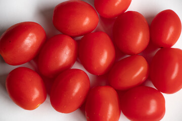 A close up of red cherry tomatoes on a white background.