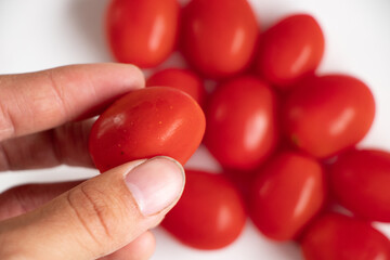 A close up of red cherry tomatoes on a white background.