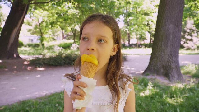 Kid girl in park face portrait eat lick ice cream on summer hot day