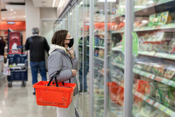 Caucasian woman in black face mask with red shopping basket