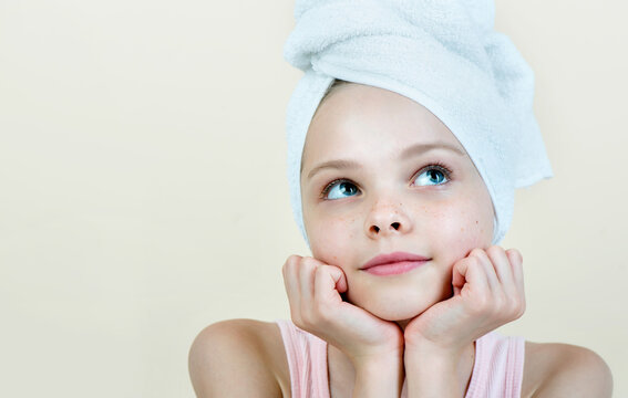 Portrait of beautiful little girl with fresh child skin. Kid in towel dreaming. Pretty baby cleansing procedures