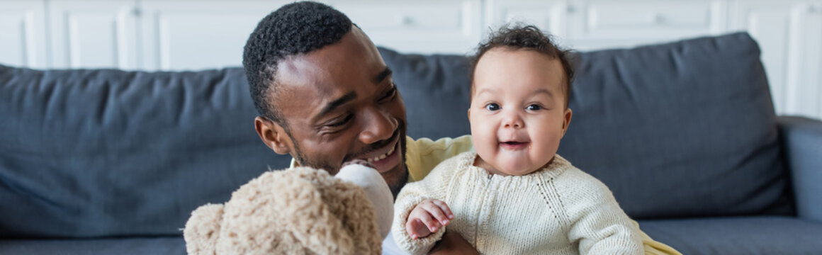 Cheerful Baby Looking At Camera Near African American Father And Teddy Bear, Banner