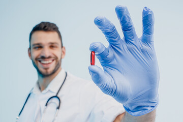 Smiling european male doctor showing medical pill