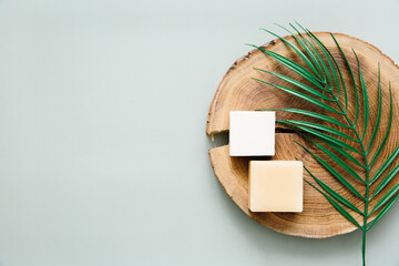 Natural handmade soap and wooden slab on a green background, top view. Cleanliness and hygiene concept.	