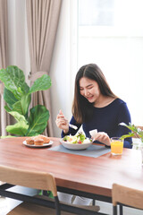Portrait of happy playful asian girl eating fresh salad in diet concept